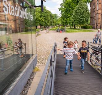 Kinder laufen die Eingangsrampe hoch zur Stadtbibliothek.