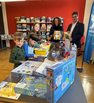 Bibliotheksleiterin Malena Kimmig und Carsten Busam vom VDI eröffnen die VDI-TechnoThek in der Jugendabteilung. Einige begeistert Kinder sind bereits am Ausprobieren der Materialien und Experimentierkästen